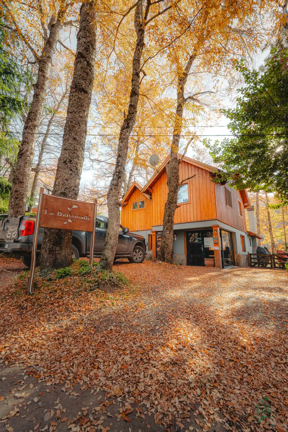 Frente de la casa de La Balconada entre el bosque en otoño
